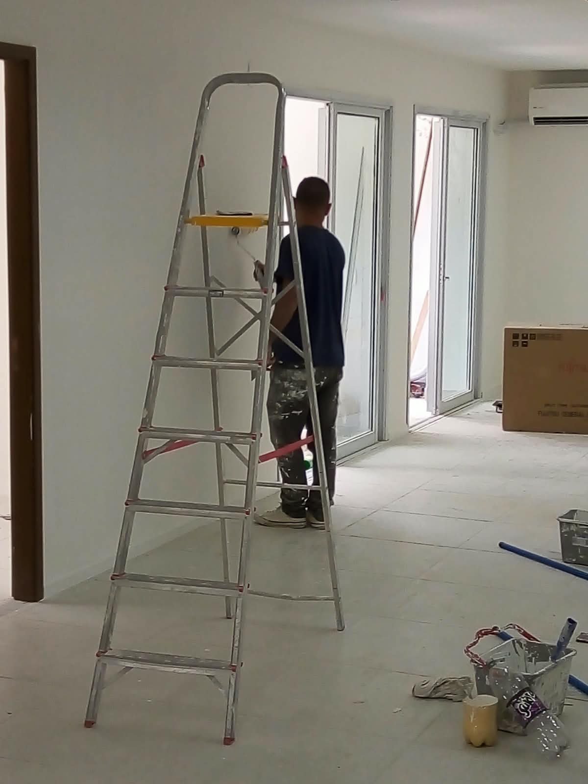 Profissional aplicando pintura com rolo em ambiente amplo
