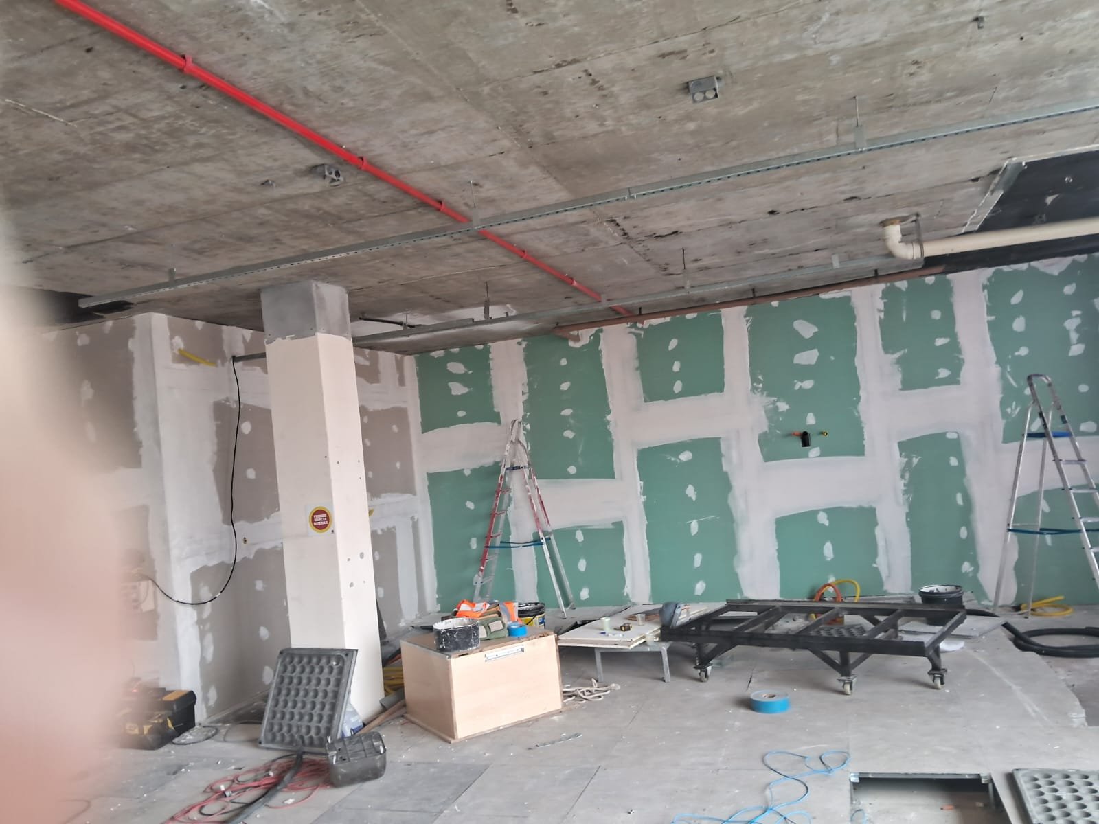 Andar comercial em obra, com paredes de drywall parcialmente revestidas e teto aparente
