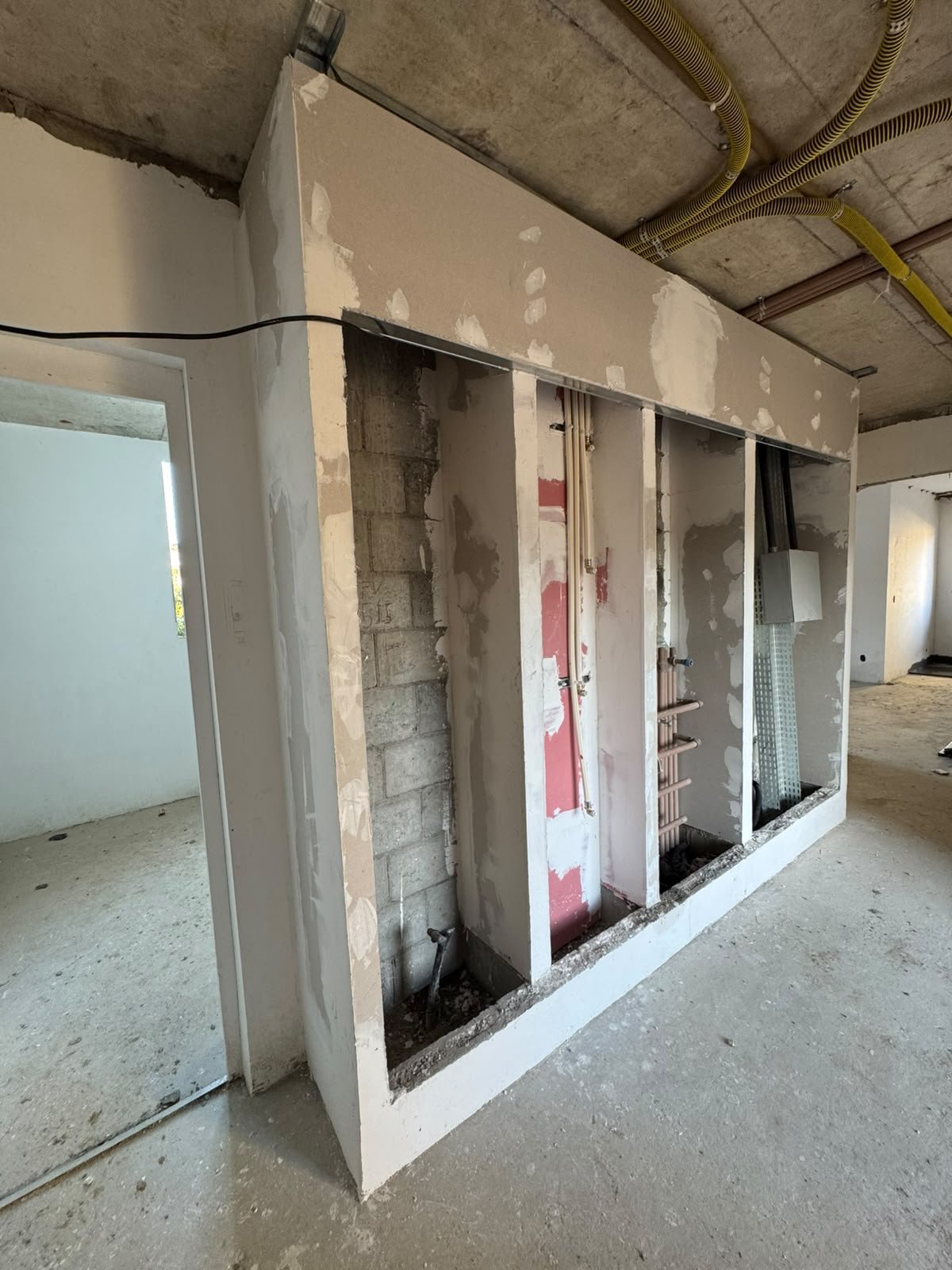 Estrutura de drywall ainda sem acabamento, com instalações à mostra
