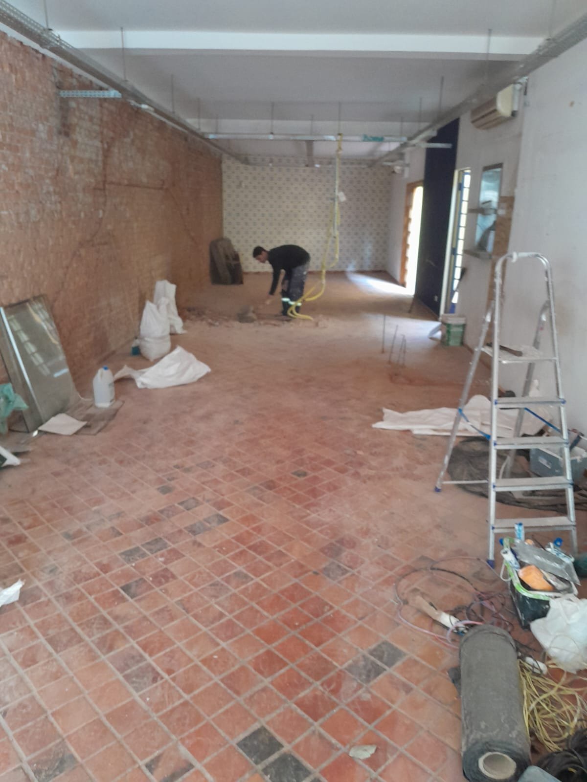 Ambiente comercial em reforma, com piso e paredes em preparo